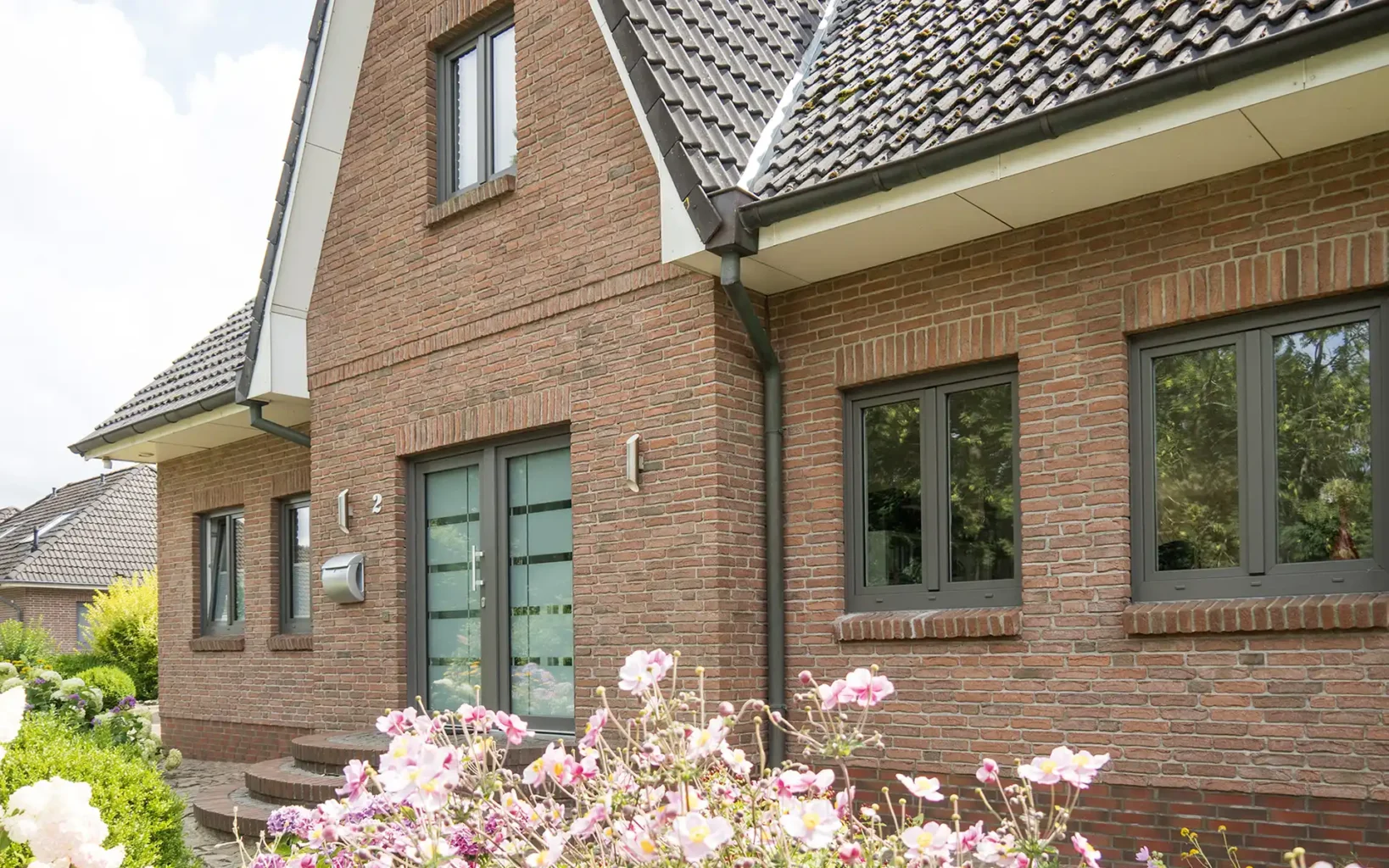 Haus aus Backstein mit modernen Aluminiumfenstern und gläserner Haustür